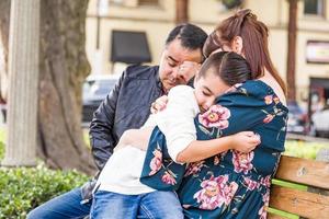 mãe caucasiana e pai hispânico consolando filho mestiço ao ar livre foto