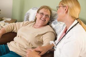 médico ou enfermeira conversando com uma mulher idosa sentada foto