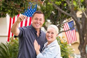casal feliz com novas chaves de casa na frente de casas com bandeiras americanas foto