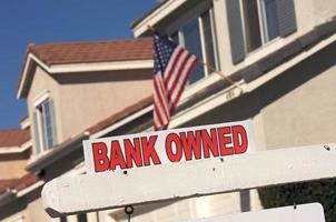 sinal imobiliário de propriedade do banco e casa com bandeira americana foto