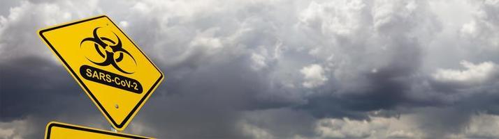 símbolo de risco biológico com sinal de estrada amarelo sars-cov-2 coronaravirus contra faixa sinistra de céu nublado e tempestuoso foto