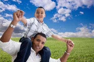 pai e filho sobre campo de grama, nuvens e céu foto