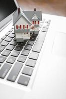 casa em miniatura no computador portátil foto
