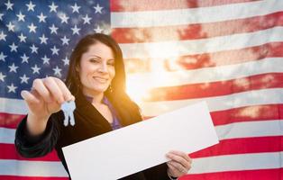 chaves de casa de mulher hispânica e placa em branco na frente da bandeira americana foto