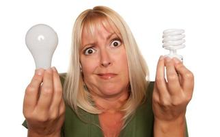mulher engraçada segurando a economia de energia e lâmpadas regulares foto