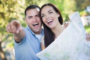 casal de raça mista olhando por cima do mapa do lado de fora juntos foto