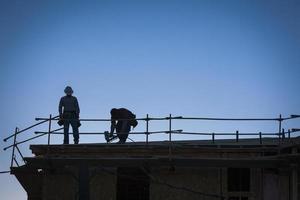 silhueta de trabalhadores da construção civil no telhado foto