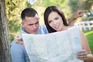 casal de raça mista perdido e confuso olhando por cima do mapa lá fora foto