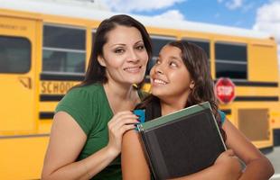 mãe hispânica e filha perto de ônibus escolar. foto