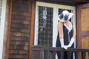 mulher atraente em roupa de vinte anos na varanda da casa antiga foto