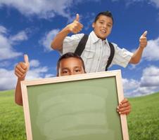 alunos com polegares para cima no campo segurando o quadro de giz em branco. foto