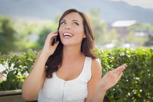 jovem adulta falando no celular ao ar livre no banco foto