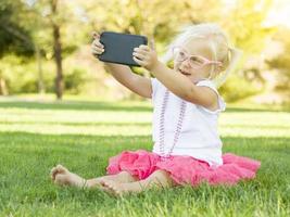 menina na grama tomando selfie com telefone celular foto