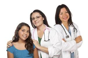 médica hispânica com paciente infantil e colega por trás foto