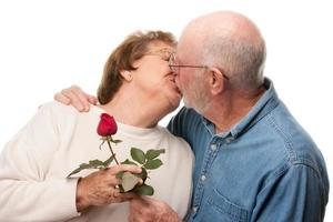 feliz casal sênior beijando com rosa vermelha foto