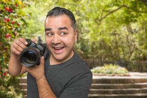 jovem fotógrafo masculino hispânico com câmera dslr ao ar livre foto