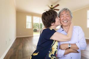 feliz casal chinês sênior se beijando dentro do quarto vazio da casa nova. foto