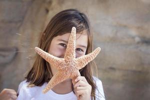 menina brincando com estrela do mar foto