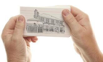 mãos masculinas segurando pilha de cartões flash com desenho de casa foto