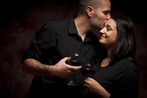 casal feliz de raça mista flertando e segurando taças de vinho foto