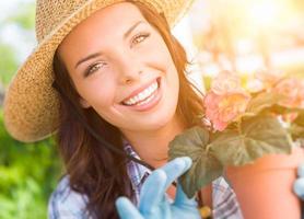 jovem adulta usando chapéu e luvas jardinagem ao ar livre foto