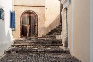 antiga passarela de paralelepípedos e degraus entre prédios em santorini, grécia foto