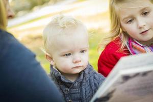 mãe lendo um livro para seus dois filhos loiros adoráveis foto