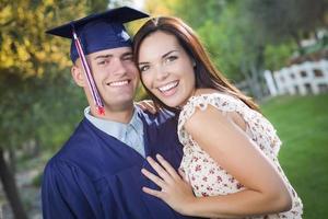 graduado masculino em boné e vestido e menina comemoram foto