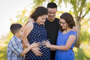família hispânica mãos na barriga da mãe grávida sentindo chute do bebê foto