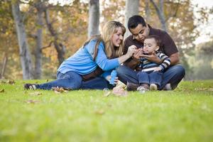 feliz família étnica de raça mista brincando com bolhas no parque foto