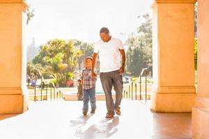 feliz pai afro-americano e filho mestiço caminhando no parque foto