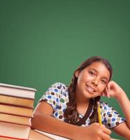 linda garota hispânica estudando na frente do quadro de giz em branco foto