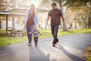 feliz família étnica de raça mista caminhando no parque foto