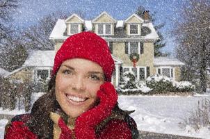 mulher de raça mista sorridente em roupas de inverno lá fora na neve foto