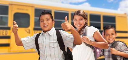 jovens hispânicos meninos e menina andando perto de ônibus escolar foto