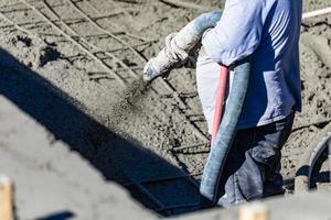 trabalhador da construção civil atirando concreto, concreto projetado ou gunite através da mangueira foto