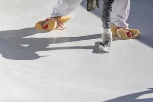 trabalhador usando esponjas em sapatos alisando reboco de piscina molhada com espátula foto