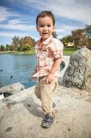 jovem menino chinês e caucasiano se divertindo no parque e lago com patos. foto