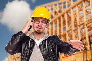 jovem trabalhador da construção civil no celular na frente de casa foto