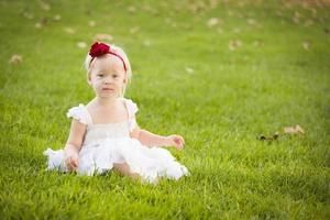 adorável menina usando vestido branco em um campo de grama foto