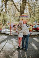 avô se divertindo com sua netinha no parque de diversões foto