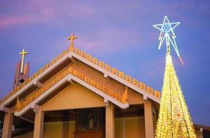 igreja católica com árvore de natal e luzes à noite foto