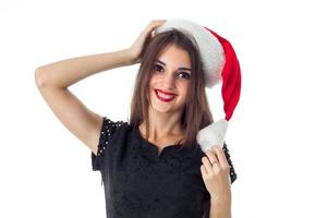 menina morena com chapéu de Papai Noel sorrindo para a câmera foto