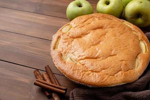 torta de maçã charlotte na mesa de madeira com maçã fresca e canela foto