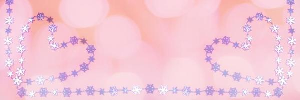 banner amplo criativo para o dia dos namorados com dois corações de flocos de neve metálicos lilás brilhantes em fundo rosa com bokeh. foto