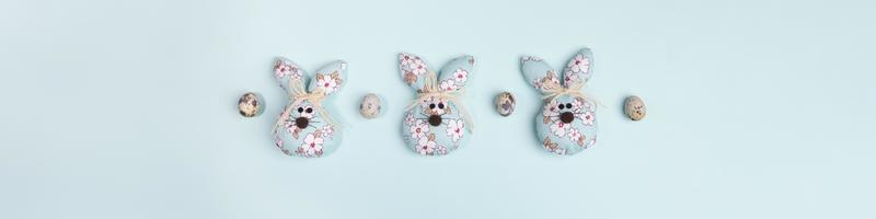 banner de páscoa com ovos de codorna e coelhinhos da páscoa têxteis diy no centro de azul claro pastel com espaço de cópia para texto. foto