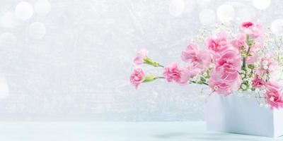cravos rosa suaves e flores gypsophila em branco ficam em cinza claro. dia das Mães. bandeira. foto