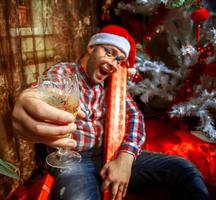 hipster bêbado com taça de champanhe debaixo da árvore de natal foto