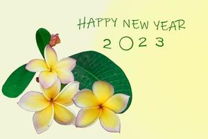 Cartão de ano novo de 2023 com fundo amarelo claro decorado com um buquê de plumerias amarelas. foco suave e seletivo. foto