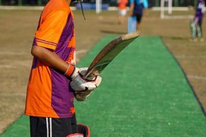 um jogador de críquete segura o bastão enquanto espera a bola de críquete. durante os treinos em campo. foco suave e seletivo. foto
